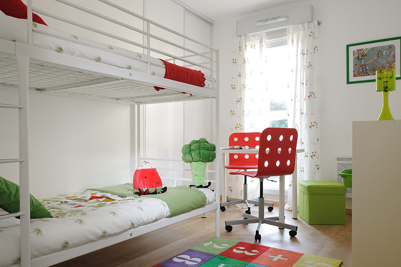 chambre d'enfants blanche avec lit superposées, décoration rouge et verte